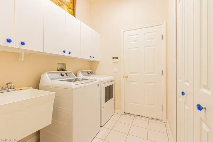 Laundry area featuring cabinet space, New GE washer and dryer, large storage closet and laundry sink.