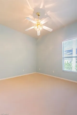 Carpeted bedroom with baseboards and a ceiling fan and large window.
