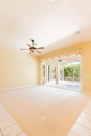 Unfurnished room featuring light carpet, ceiling fan, light tile patterned floors, and a textured ceiling