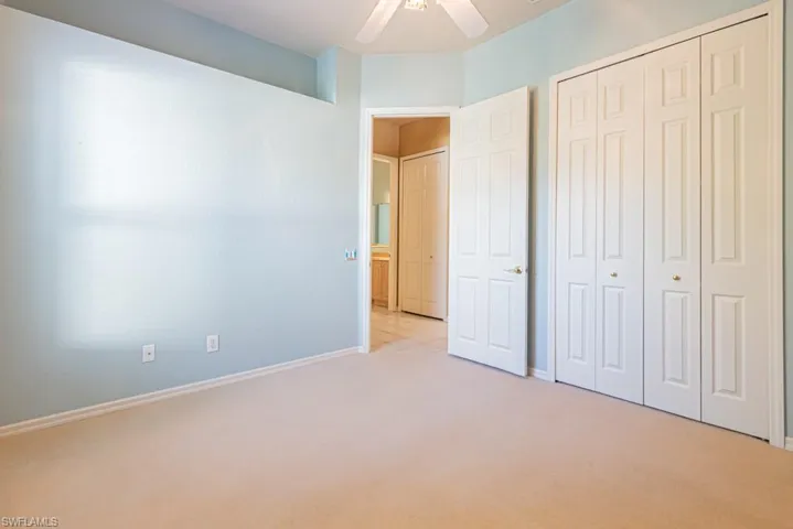 Unfurnished bedroom featuring light colored carpet, a closet, and ceiling fan