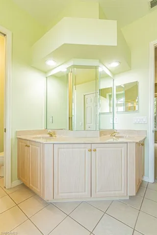 Full bath with light tile patterned floors and double vanity