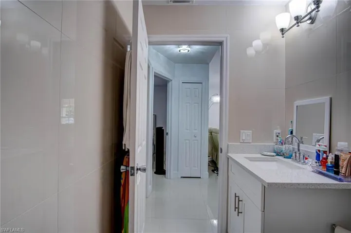 Bathroom featuring tile patterned floors, tile walls, and vanity