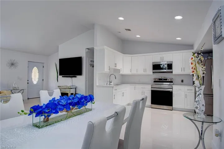 Kitchen featuring white cabinetry, lofted ceiling, stainless steel appliances, and sink