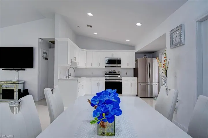 Kitchen with appliances with stainless steel finishes, backsplash, sink, and vaulted ceiling