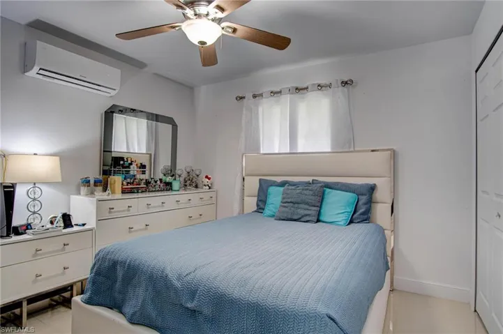 Bedroom with a wall mounted AC, ceiling fan, and a closet