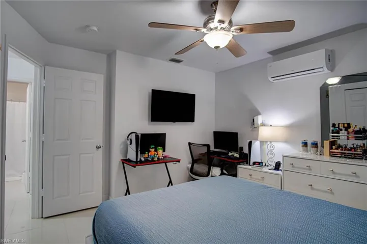 Tiled bedroom featuring ceiling fan and a wall mounted air conditioner