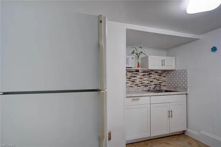 Kitchen with backsplash, sink, white appliances, and white cabinets