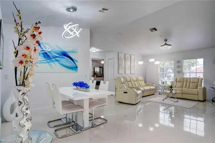 Living room featuring lofted ceiling, light tile patterned floors, and an inviting chandelier