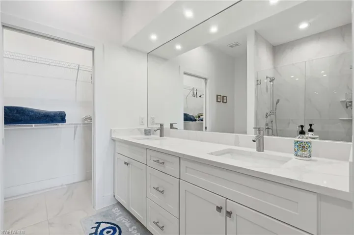 Double vanity with integrated sinks, white cabinetry, and a full-width mirror