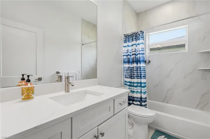 Bathroom featuring a single vanity with stone countertop, integrated sink, and modern faucet