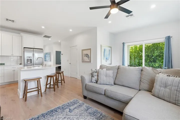 Open-concept living space with light wood-finish flooring, recessed lighting, and a contemporary ceiling fan