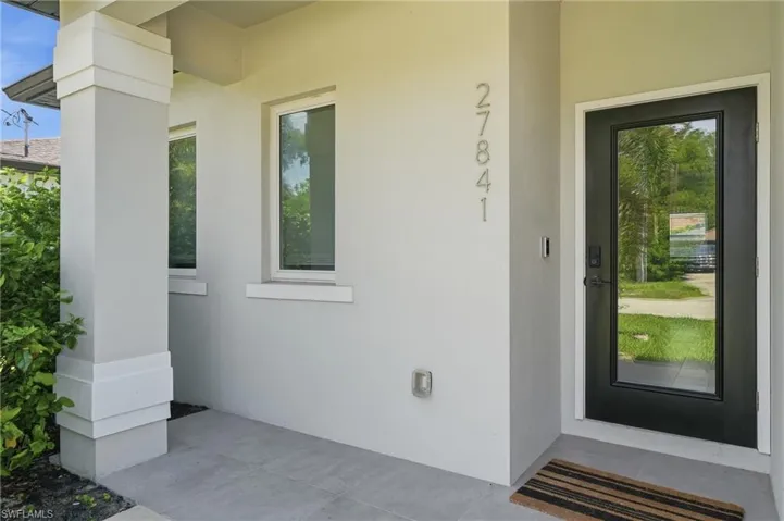 Modern entryway featuring a full-light black-framed door, a contemporary light fixture, and large format concrete-look floor tiles