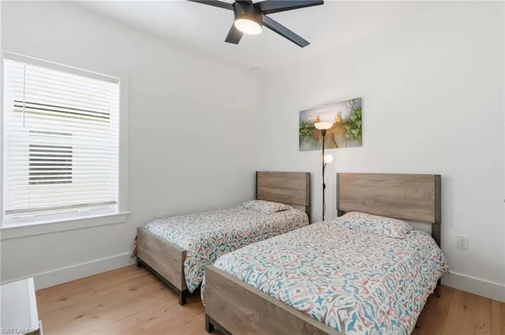 Bright room with light wood-finish flooring, a ceiling fan, and white walls