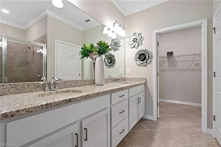 Double vanity with granite countertops, undermount sinks, and white cabinetry