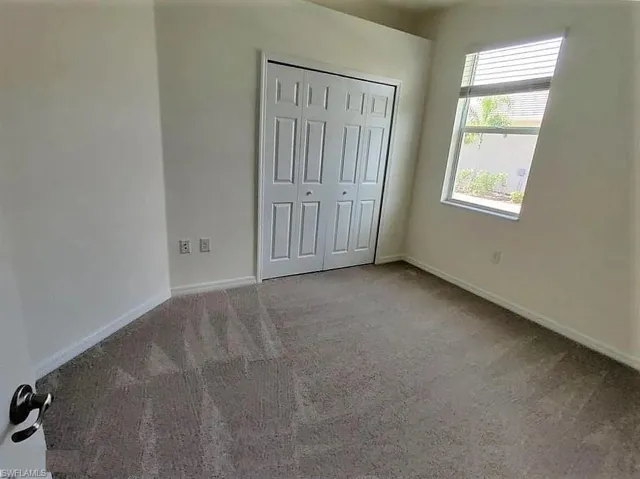 Window with blinds, folding closet doors, and neutral carpeting