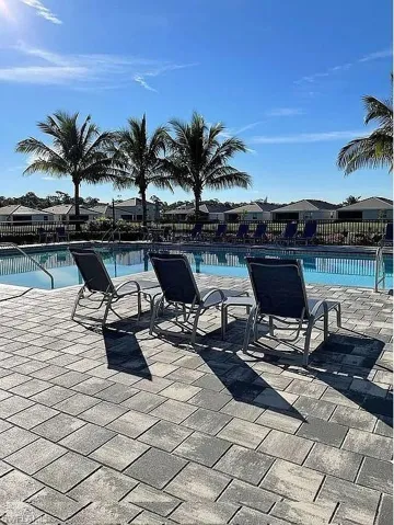 Swimming pool with integrated steps, surrounded by multi-toned paver decking, and framed by mature palm trees
