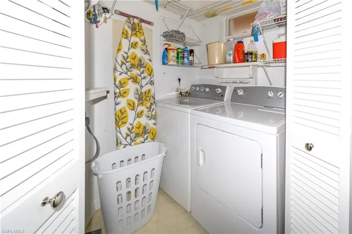 Dedicated laundry space featuring a white washer and dryer pair, louvered bi-fold doors, and integrated wire shelving
