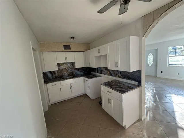 Kitchen featuring arched walkways, decorative backsplash, and light tile patterned floors