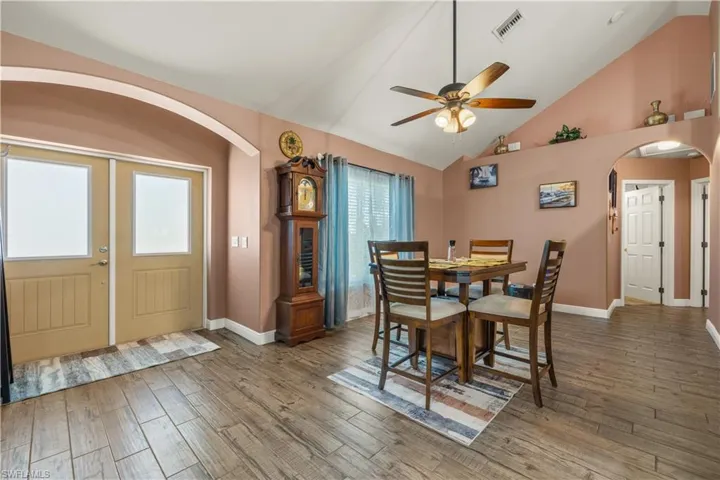 Entryway featuring double doors with frosted glass panels, wood-finish flooring, vaulted ceilings, and an arched doorway leading to an interior space
