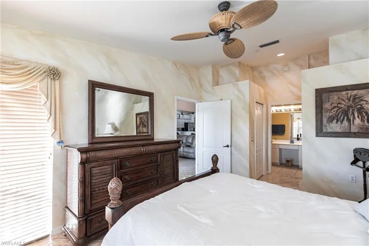 Tiled bedroom featuring ceiling fan, a closet, and ensuite bath