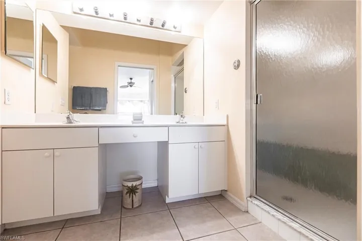 Bathroom featuring tile patterned floors, vanity, ceiling fan, and a shower with shower door