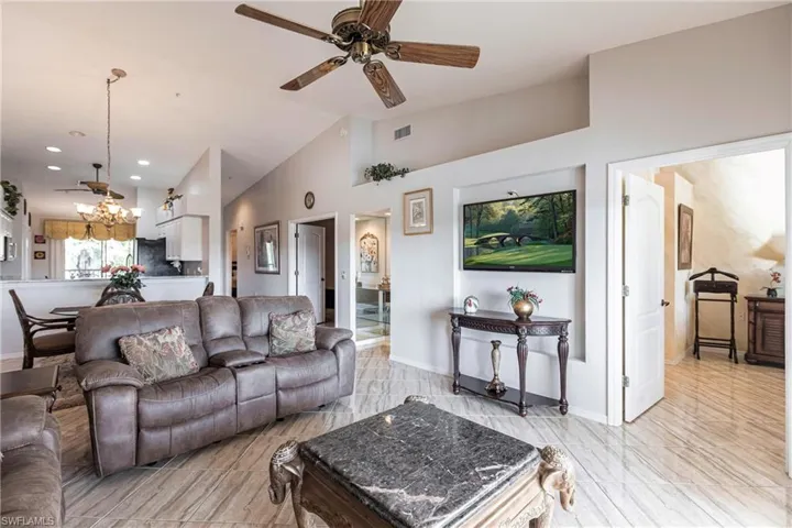Living room with high vaulted ceiling and ceiling fan with notable chandelier