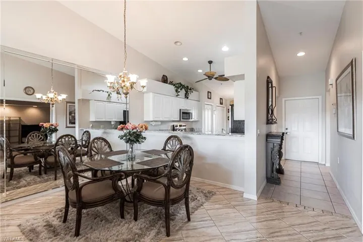 Dining space featuring ceiling fan with notable chandelier and high vaulted ceiling