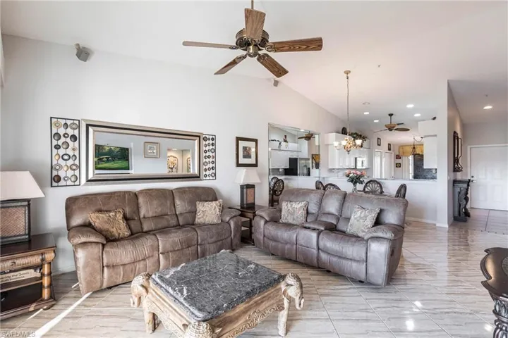 Living room featuring ceiling fan with notable chandelier and lofted ceiling