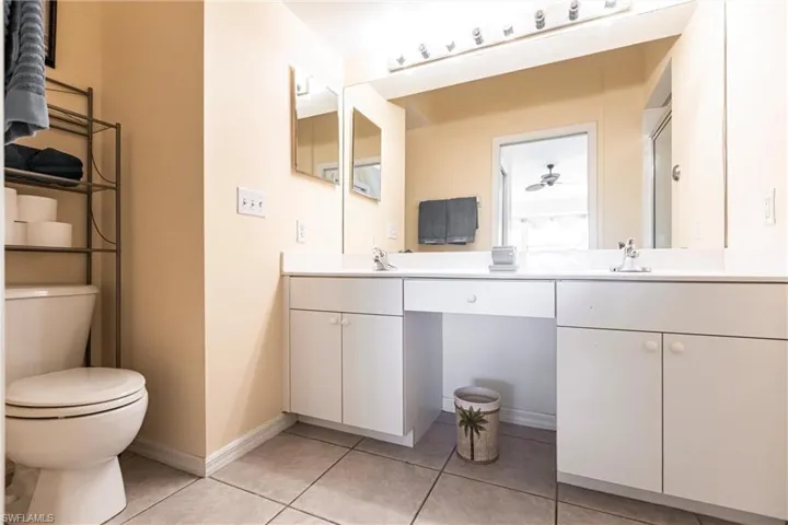 Bathroom with vanity, a shower, tile patterned flooring, ceiling fan, and toilet