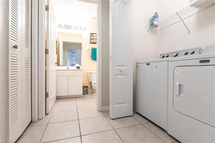Laundry area with washing machine and dryer and light tile patterned flooring