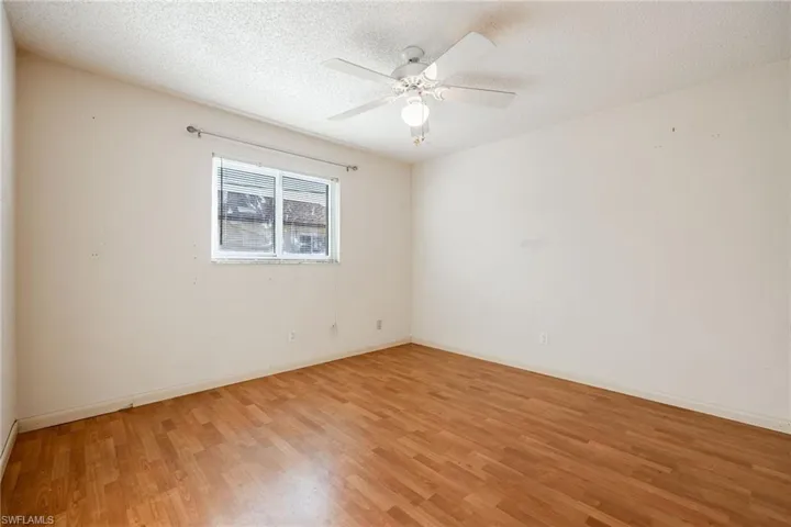 Unfurnished room featuring wood-type flooring, ceiling fan, and a textured ceiling