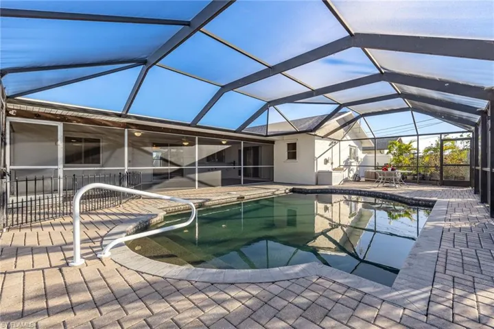 View of pool with a patio area and glass enclosure
