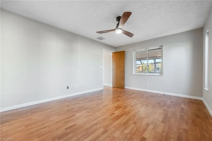Empty room featuring ceiling fan, a textured ceiling, and light wood-type flooring