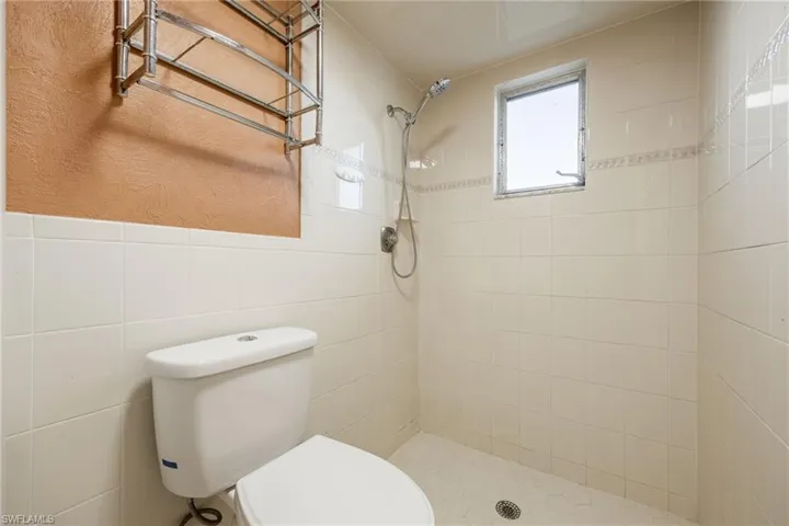 Bathroom with toilet, tile walls, and a tile shower
