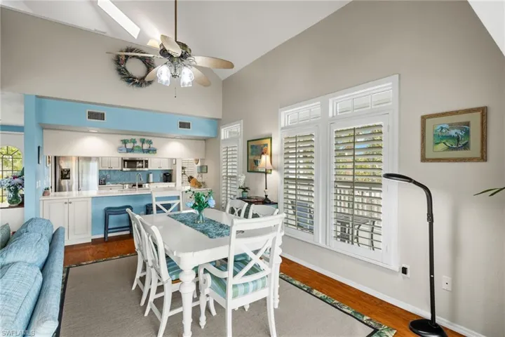 Dining space with ceiling fan, sink, dark hardwood / wood-style floors, and high vaulted ceiling