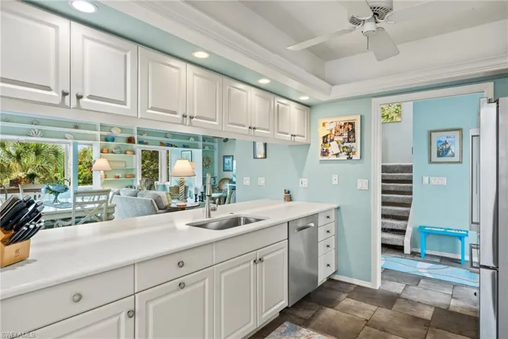 Kitchen with sink, stainless steel appliances, white cabinetry, and ceiling fan