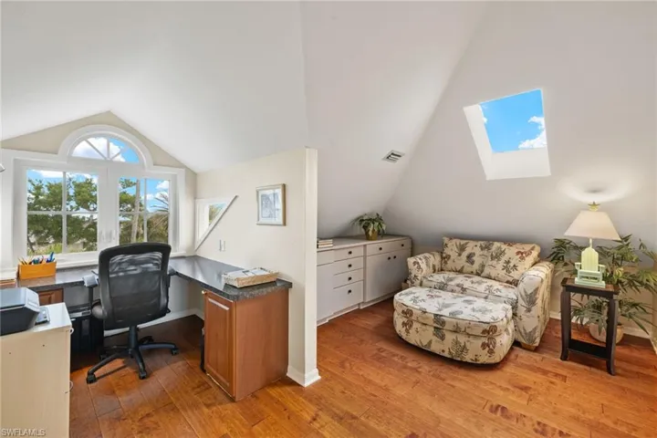 Office space with lofted ceiling with skylight and wood-type flooring