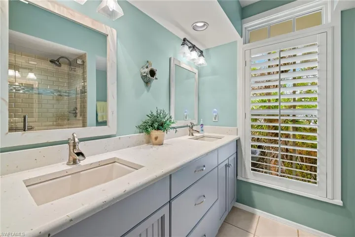 Bathroom with vanity, walk in shower, and tile patterned flooring