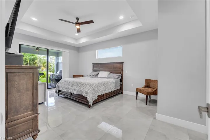 Bedroom with access to exterior, a ceiling fan, a tray ceiling, and recessed lighting