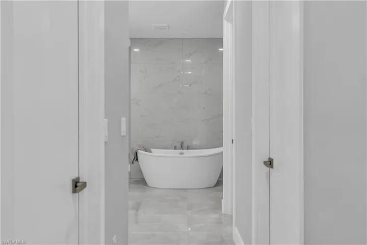 Bathroom with a freestanding tub, tile walls, and light marble finish flooring