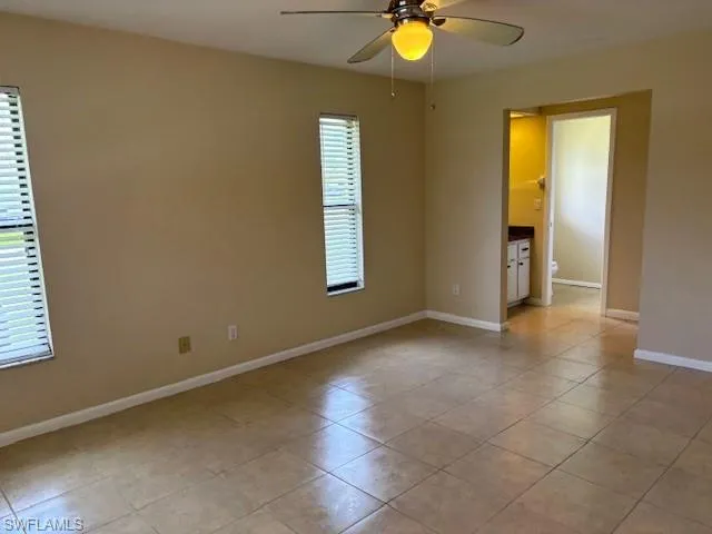 Empty room featuring a healthy amount of sunlight, light tile patterned floors, and ceiling fan