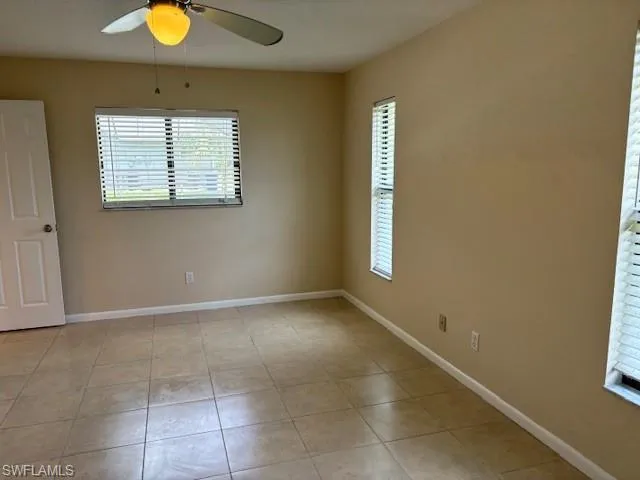 Empty room with light tile patterned floors and ceiling fan