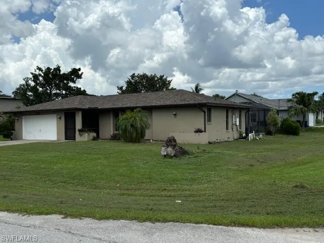 View of front of property featuring a garage and a front lawn