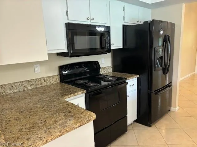 Kitchen featuring white cabinets, black appliances, and light tile patterned floors
