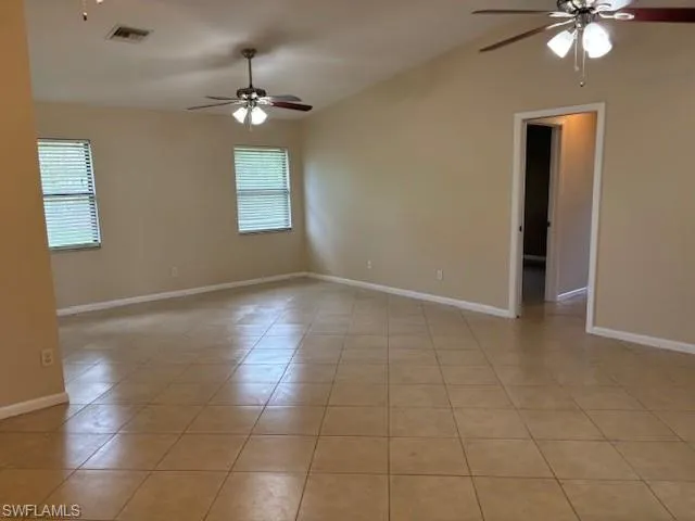 Empty room with light tile patterned floors and ceiling fan