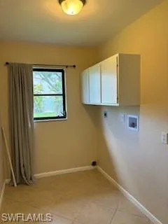 Laundry area featuring hookup for a washing machine, light tile patterned floors, hookup for an electric dryer, and cabinets