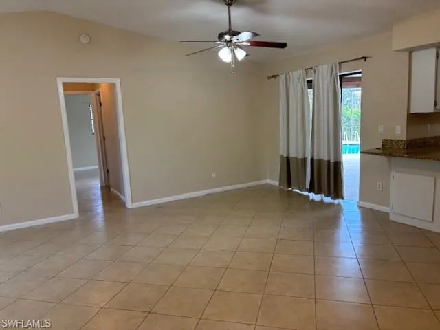 Unfurnished living room featuring light tile patterned floors, vaulted ceiling, and ceiling fan