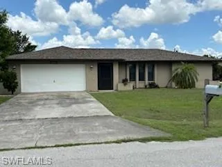 Single story home featuring a garage and a front lawn