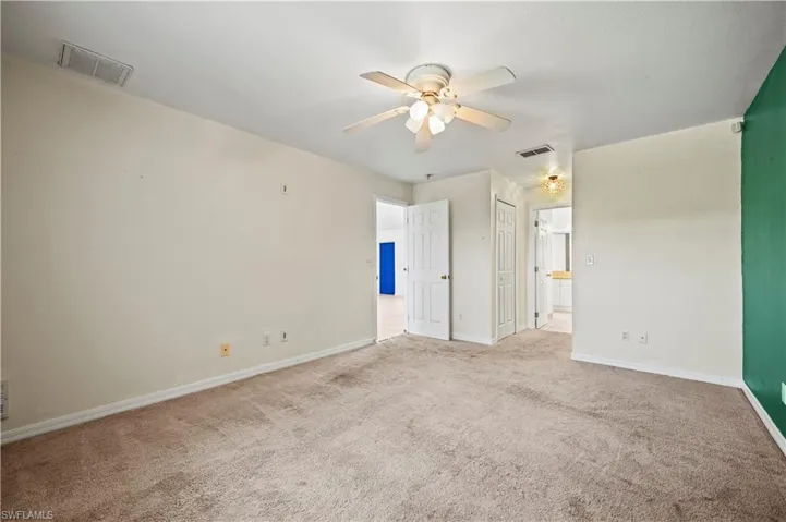 Unfurnished bedroom with carpet flooring, baseboards, connected bathroom, and ceiling fan