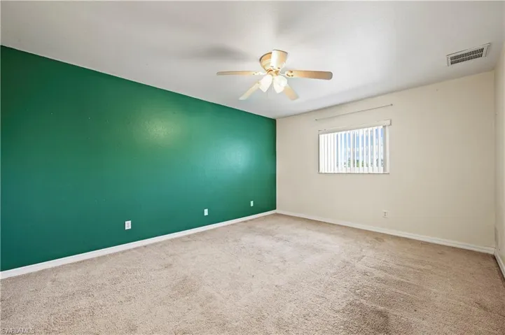 Empty room featuring ceiling fan, carpet, and baseboards